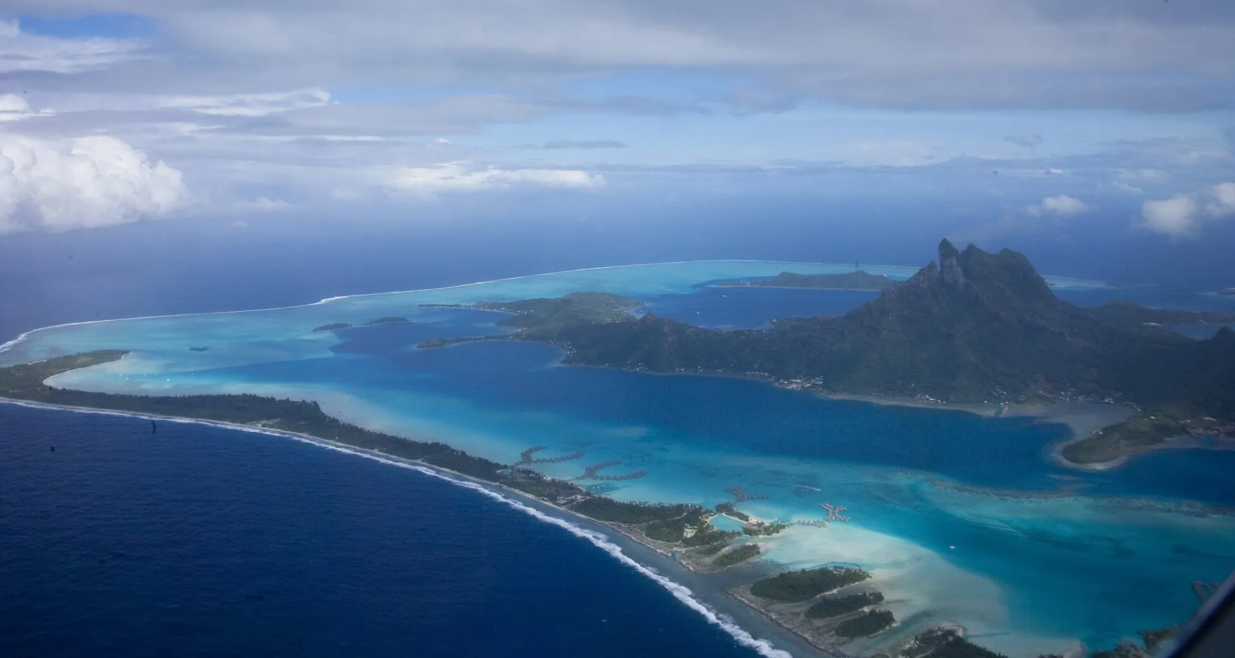 Luchtfoto van Bora Bora met Mount Otemanu, de turquoise lagune en overwater-bungalows zichtbaar op de motus